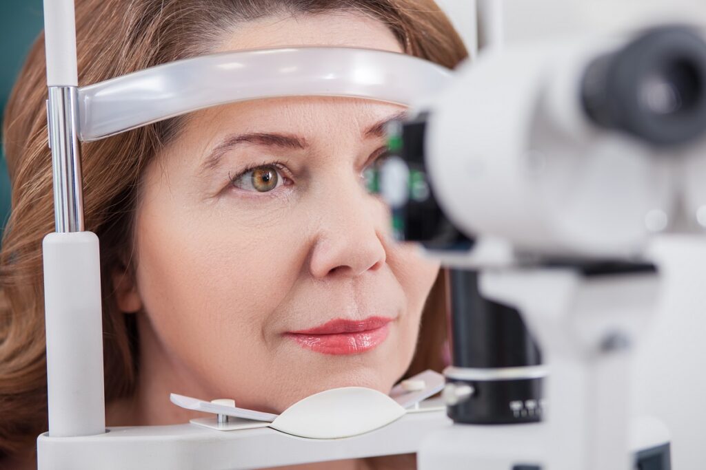 A woman receiving an eye exam from an eye examination machine