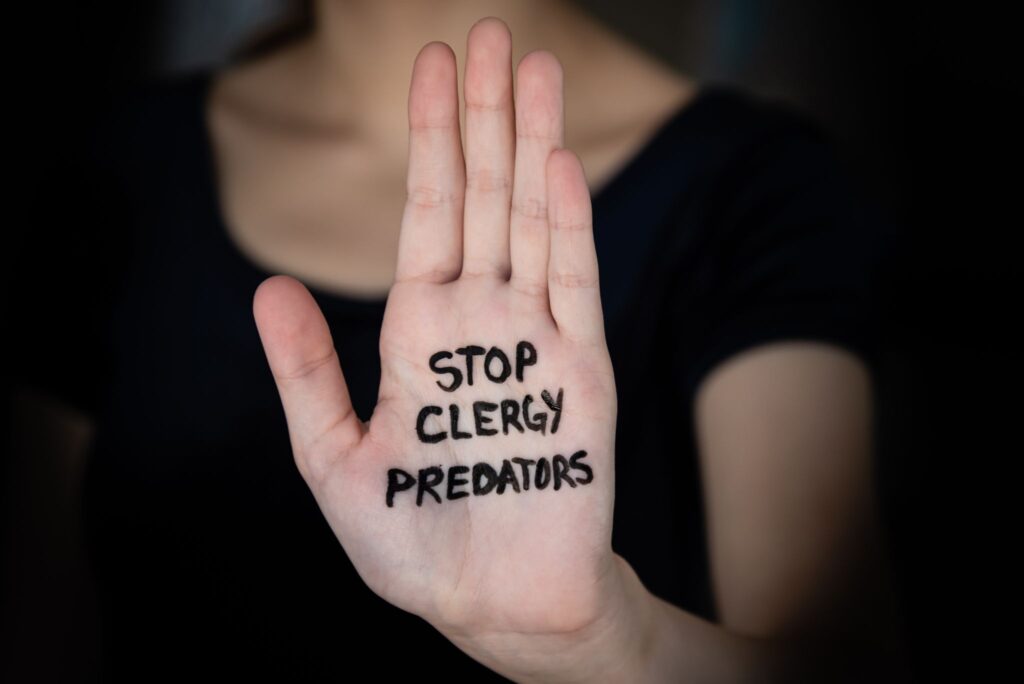 Woman with words Stop Clergy Predators written on hand