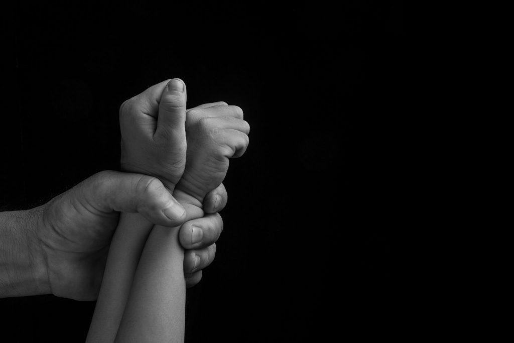 Man hand holding tight children hands