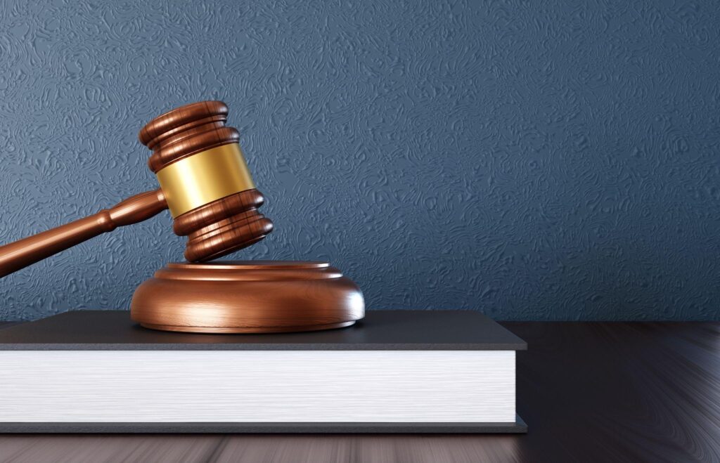Wooden judge gavel with book on the desk near blue wall. Law and justice concept.