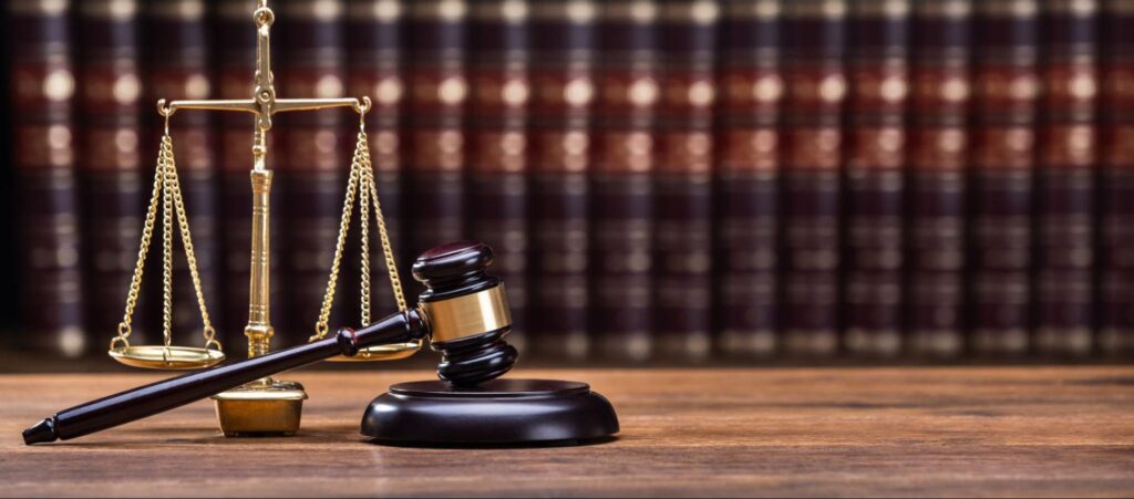 Gavel In Front Of Books With Golden Scale.