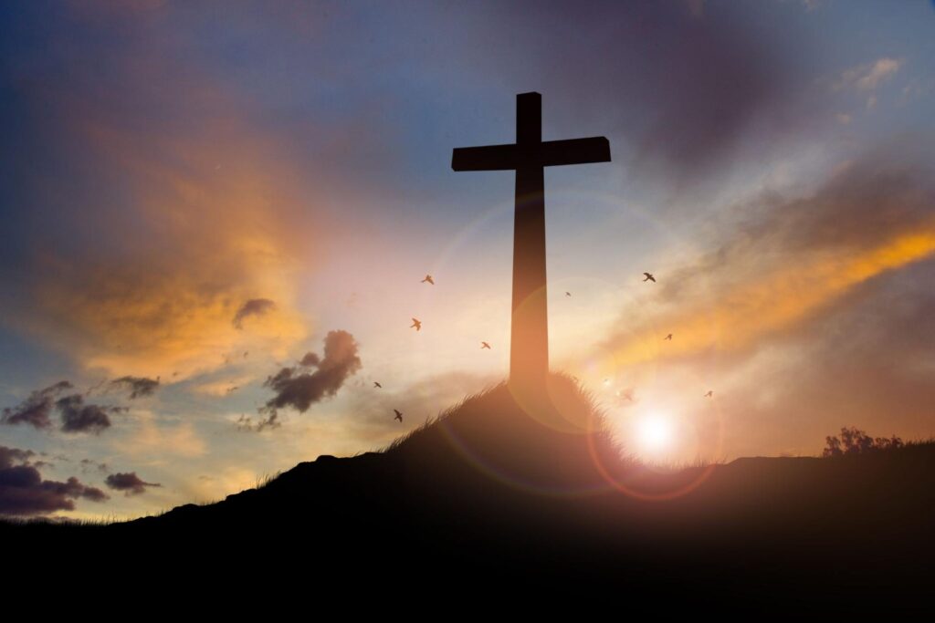 Cross on blurry sunset background .
