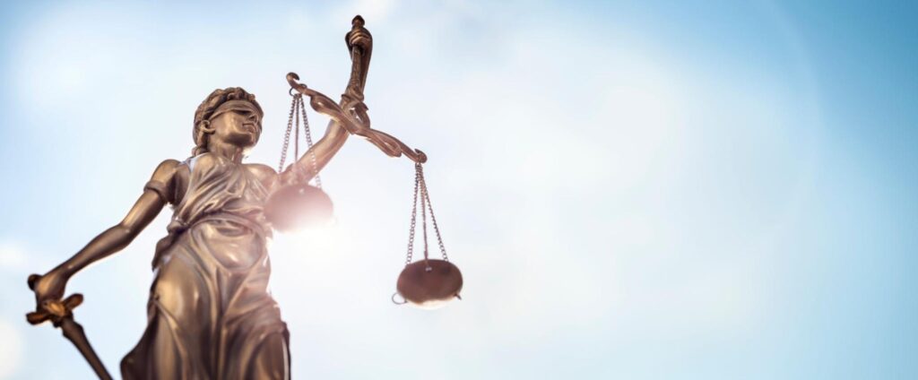 Legal law concept statue of Lady Justice with scales of justice sky background.