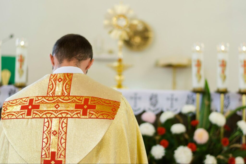 Indoor portrait of Catholic priest from back.