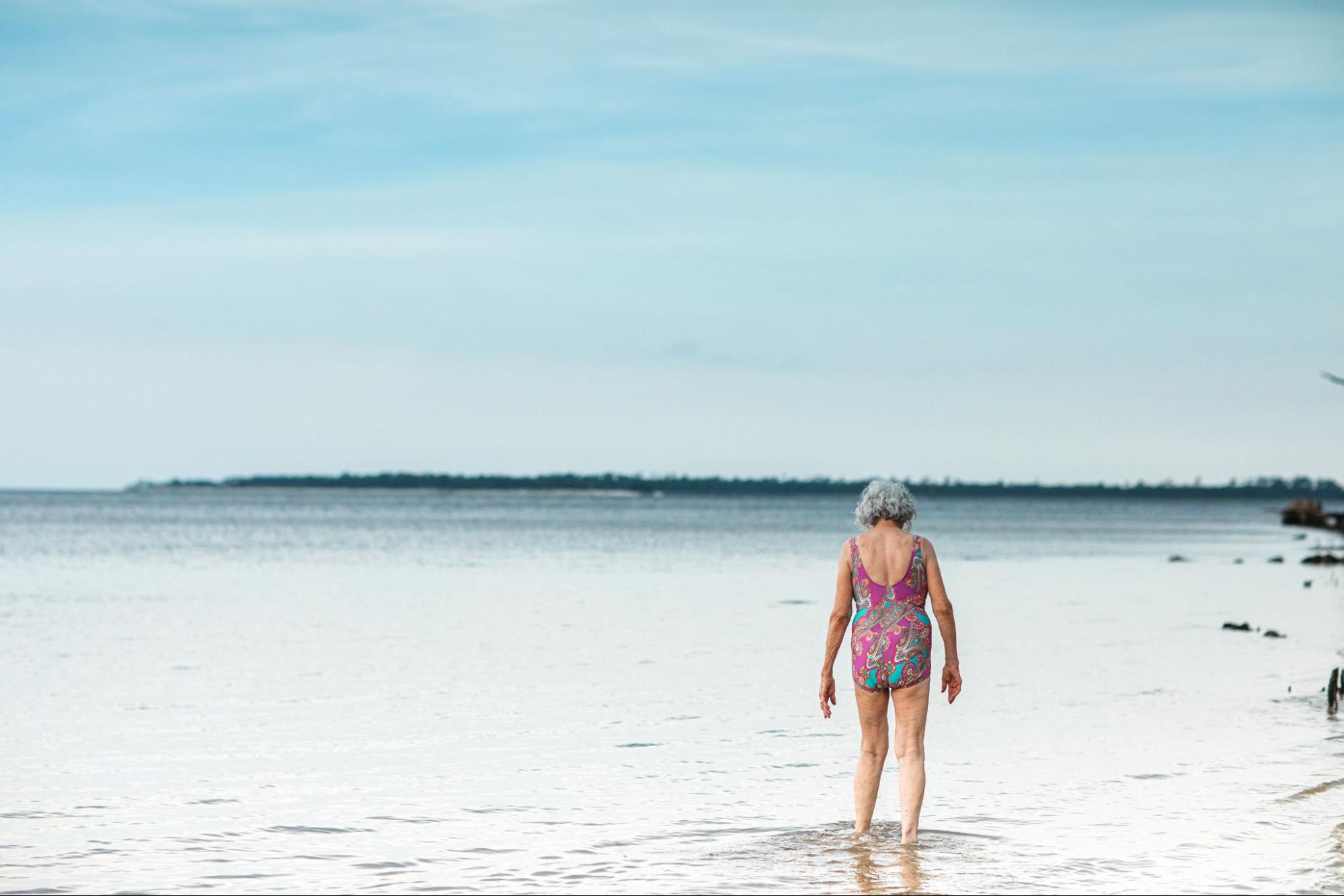 Elderly Woman in her 80's looking for shells on the sandy at the Florida Beach.