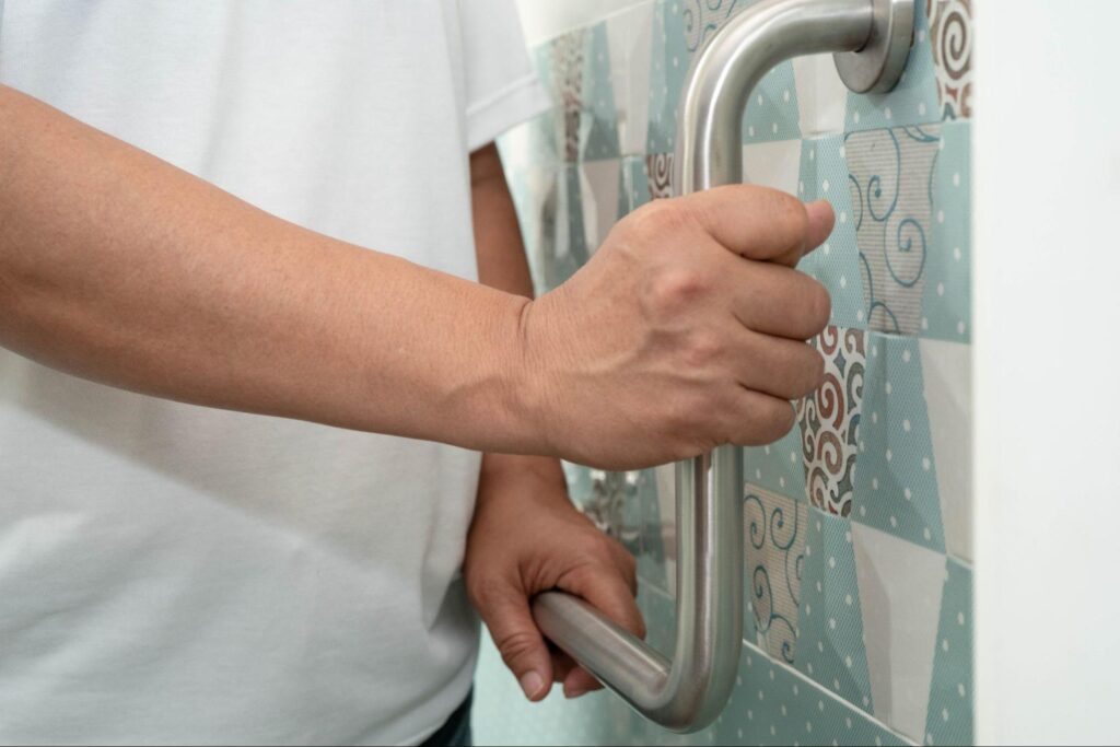 Asian woman patient use toilet support rail in bathroom, handrail safety grab bar, security in nursing hospital.